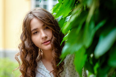 Close-up portrait of beautiful young woman by plants