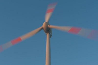 Low angle view of wind turbine against blue sky