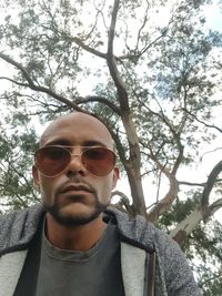 Portrait of young man wearing sunglasses against trees