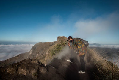 Man climbing on mountain against sky