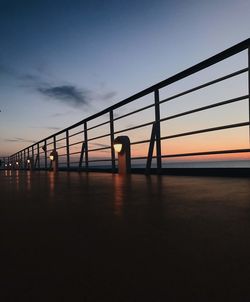 Silhouette bridge over calm sea at sunset