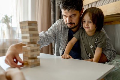 Father teaching son to play block removal game at home