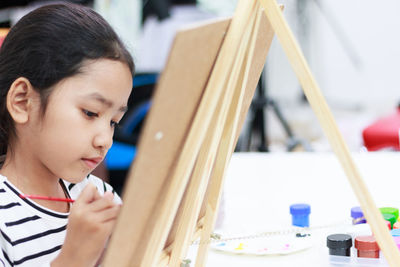 Close-up of girl painting on easel