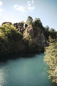 Scenic view of cliff by trees against sky