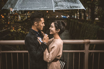Young couple standing on railing during rain