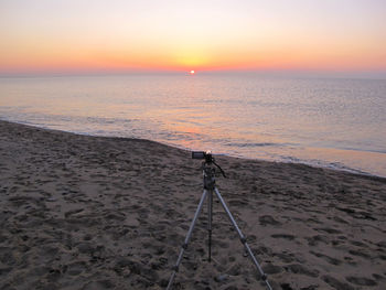 Tripod on sand at beach during sunset