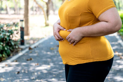 Midsection of woman holding yellow while standing outdoors