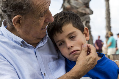 Close-up of senior man holding grandson cheek