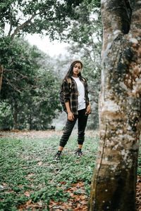 Full length of woman standing by tree in forest