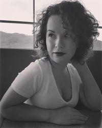 Close-up portrait of young woman sitting against window