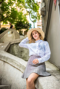 Smiling young woman sitting on retaining wall