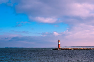 Lighthouse by sea against sky