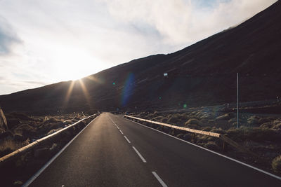 Road leading towards mountain against sky