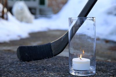 Close-up of burning candle on glass