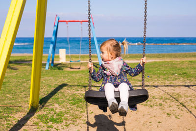 Girl sitting on swing at playground