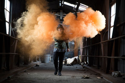 Full length of man holding distress flare while walking in abandoned workshop