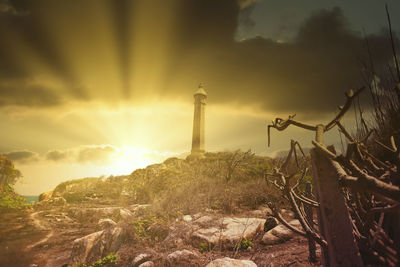 Lighthouse amidst buildings against sky during sunset