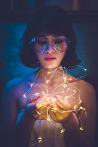 Close-up portrait of young woman holding sunglasses