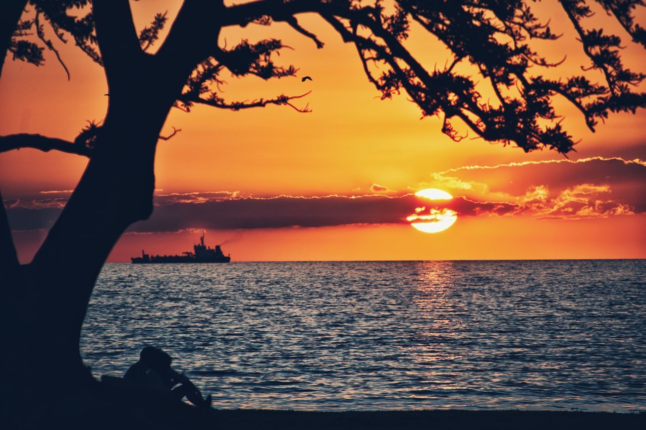 SILHOUETTE MAN ON SEA AGAINST ORANGE SKY