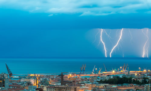 Aerial view of city by sea against sky