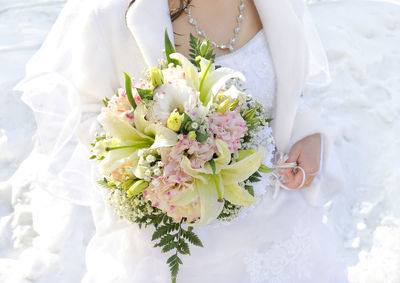Midsection of bride holding roses bouquet