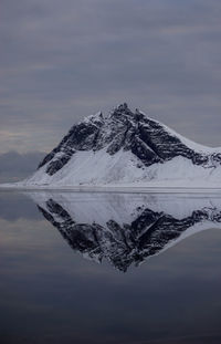 Scenic view of lake by snowcapped mountain against sky during winter