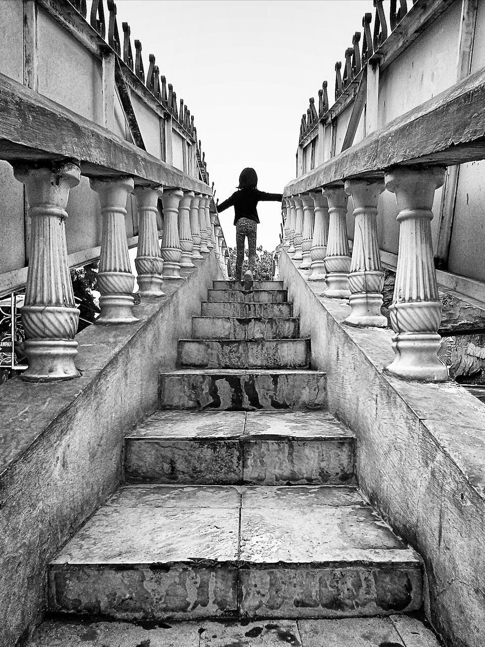 REAR VIEW OF WOMAN STANDING ON STAIRCASE