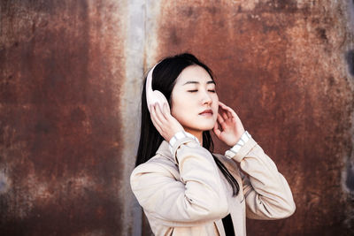 Relaxed business woman with eyes closed listening to music on headphones and mobile phone in city