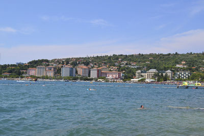 Scenic view of sea by buildings against sky