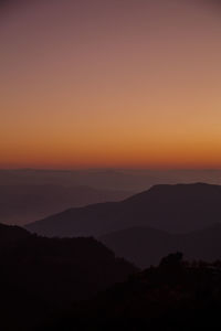 Scenic view of silhouette mountains against orange sky