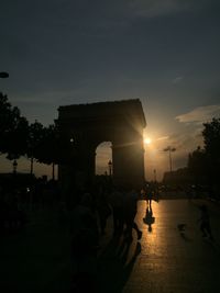 People at illuminated town square during sunset