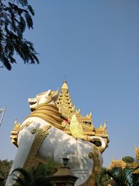 Low angle view of statue against temple building against clear sky