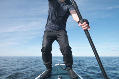 Man holding boat in sea against sky