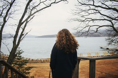 Rear view of woman looking at lake against sky