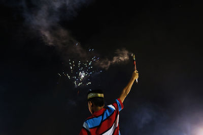 Low angle view of lit firework against sky at night