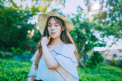 Portrait of young woman standing against plants