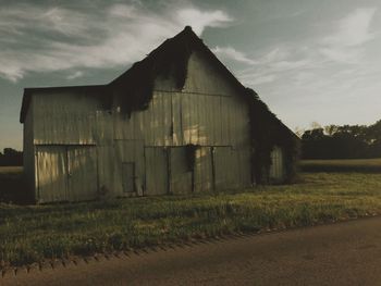 Barn on field against cloudy sky