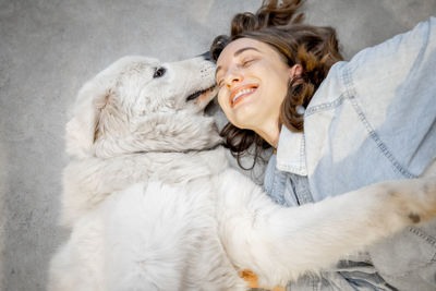 Smiling woman lying on floor with dog at home