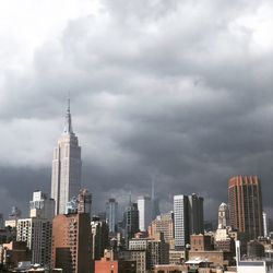 Modern buildings in city against cloudy sky