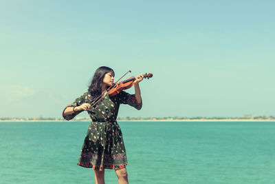 Woman standing in sea against sky