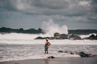 Rear view of man on beach against sky