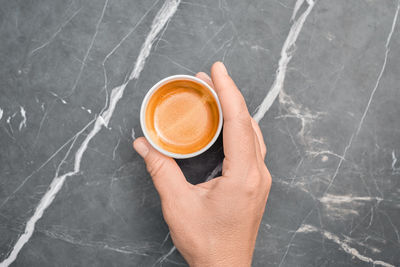 Cropped hand of person holding coffee on table