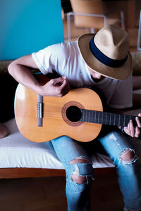 High angle view of teenager playing guitar while sitting on bed