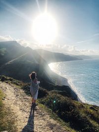 Woman standing on sea against sky on sunny day