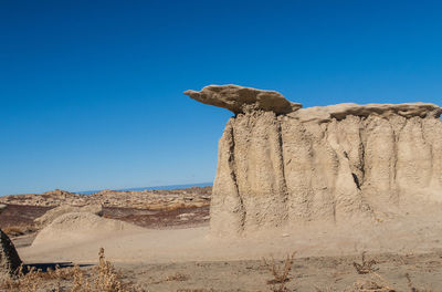 Bisti badlands landscape of dramatic grey hoodoos or caprock formations against blue sky 