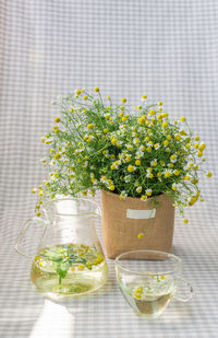 Close-up of flowers with jar and cup