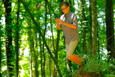 Boy standing in foret, looking smartphone