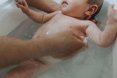 Midsection of woman with baby hands in bathroom