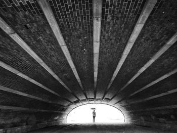 Mid distance view of person holding umbrella seen from tunnel