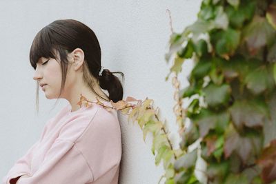 Side view of woman looking against wall